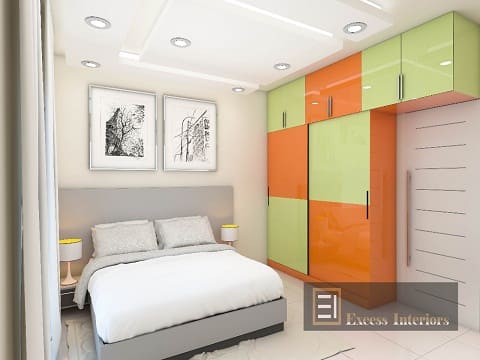 Imagine lying in bed and gazing up at a stunning false ceiling with bright lights that adds a touch of sophistication to your bedroom.This image incorporates the same with an orange and paster green themed wardrobe
