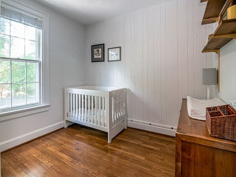 The furniture in this kids' room is a perfect match of comfort and functionality. Traditional wooden flooring with white walls are paired with modern, space-saving designs for this baby room.