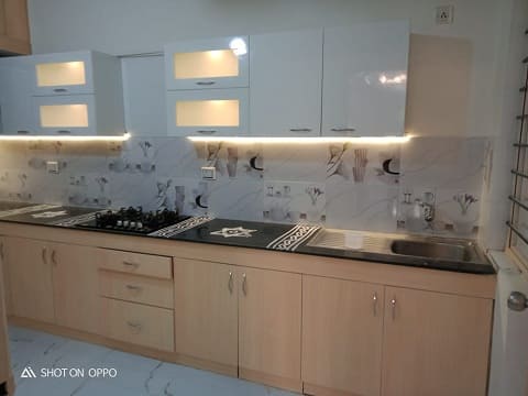 kitchen designed with light natural wood shades especially for the cabinets and white laminate as a contrast with led fittings inside the cabinets on vtop shelves for more visibilty 