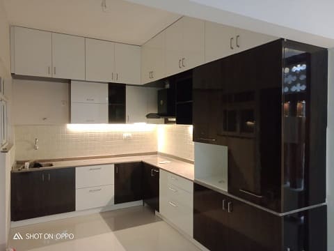 A  perfect L shaped kitchen for a family using black and white glossy laminates for the cabinets to match the customers preference and give it a classy look designed by the best modular kitchen interior designers in Hyderabad