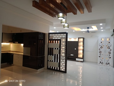 A live image with the living room and kitchen with beautiful partitions designed to go swith the colour palette exclusively designed by the top-notch living room interior designers in hyderabad